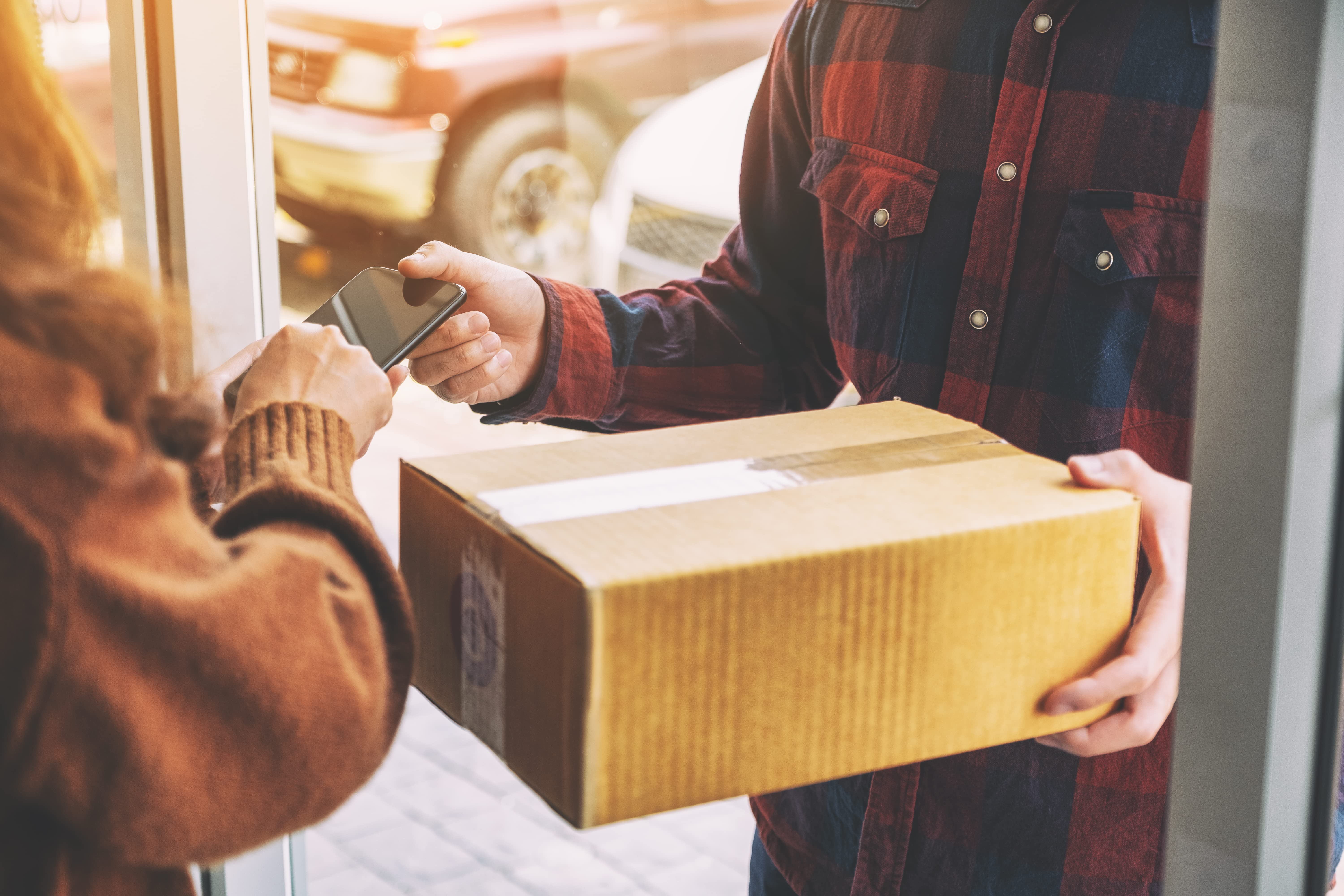 Young couriers cooperating while unloading packages from deliver Delivery men loading carboard boxes in a van while getting ready for the shipment.