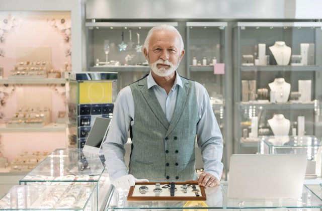 Senior man in jewelry store selling luxury watches looking at camera Senior man in jewelry store selling luxury watches